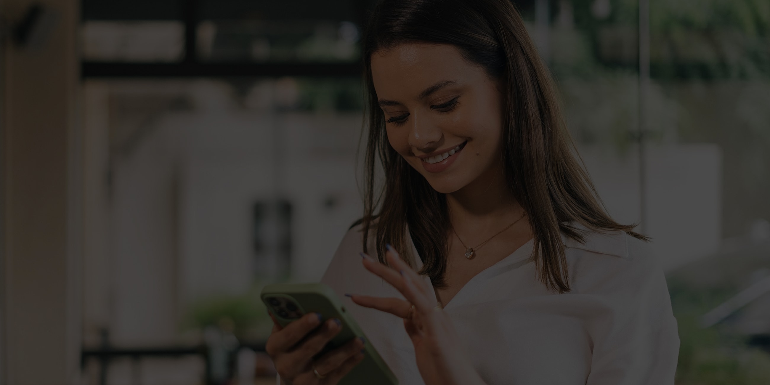 Smiling woman using smartphone in a café.