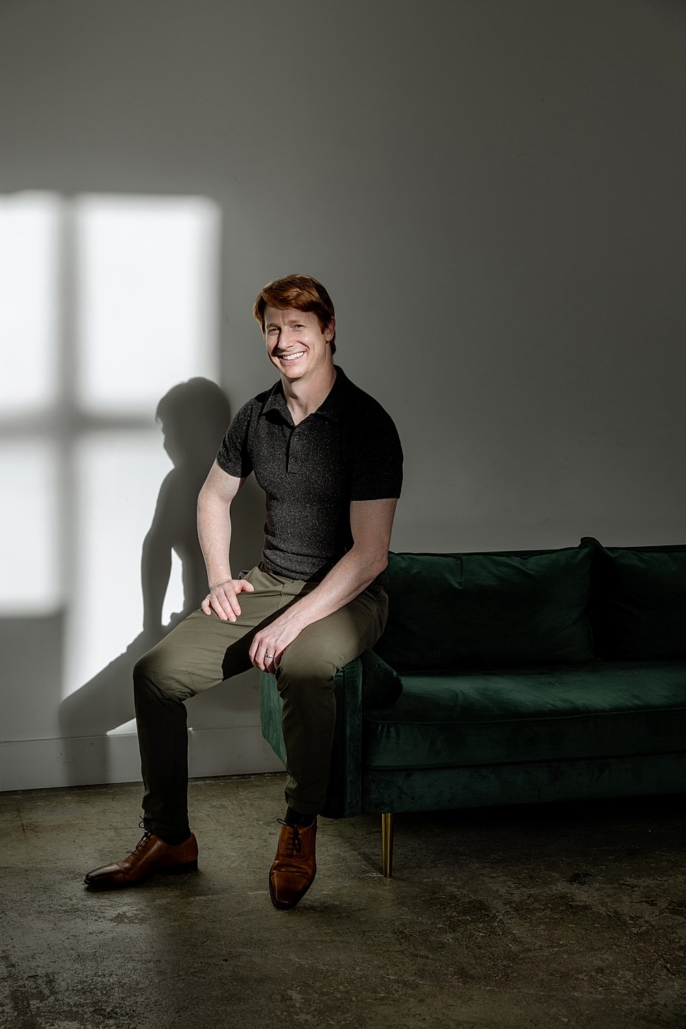 Smiling man sitting on a green couch.