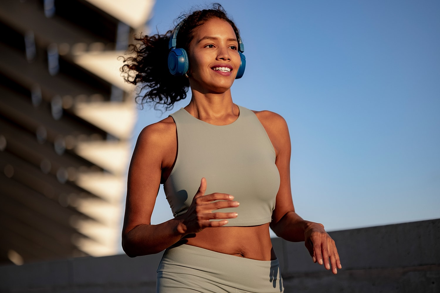 Woman jogging outdoors wearing headphones and athletic wear.