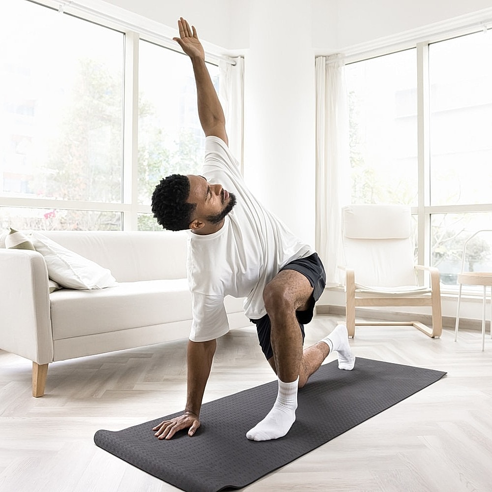 Man practicing yoga at home on mat.