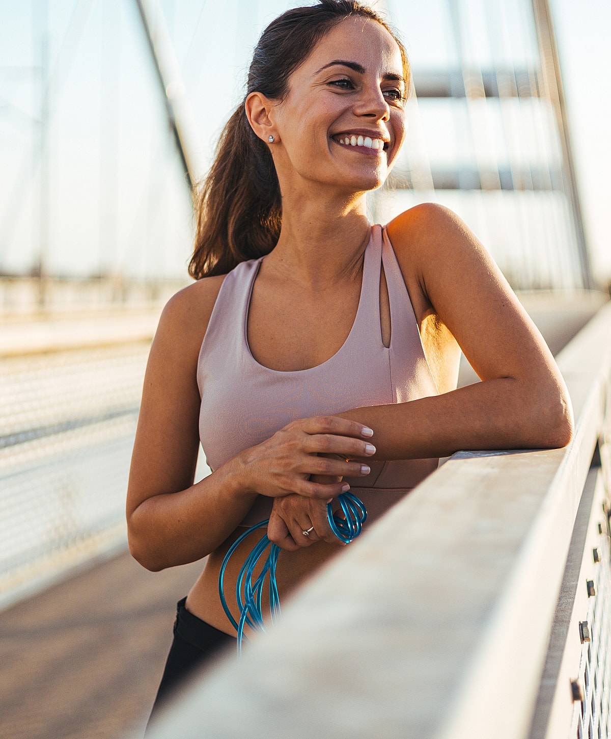 Smiling woman in athletic wear on bridge.