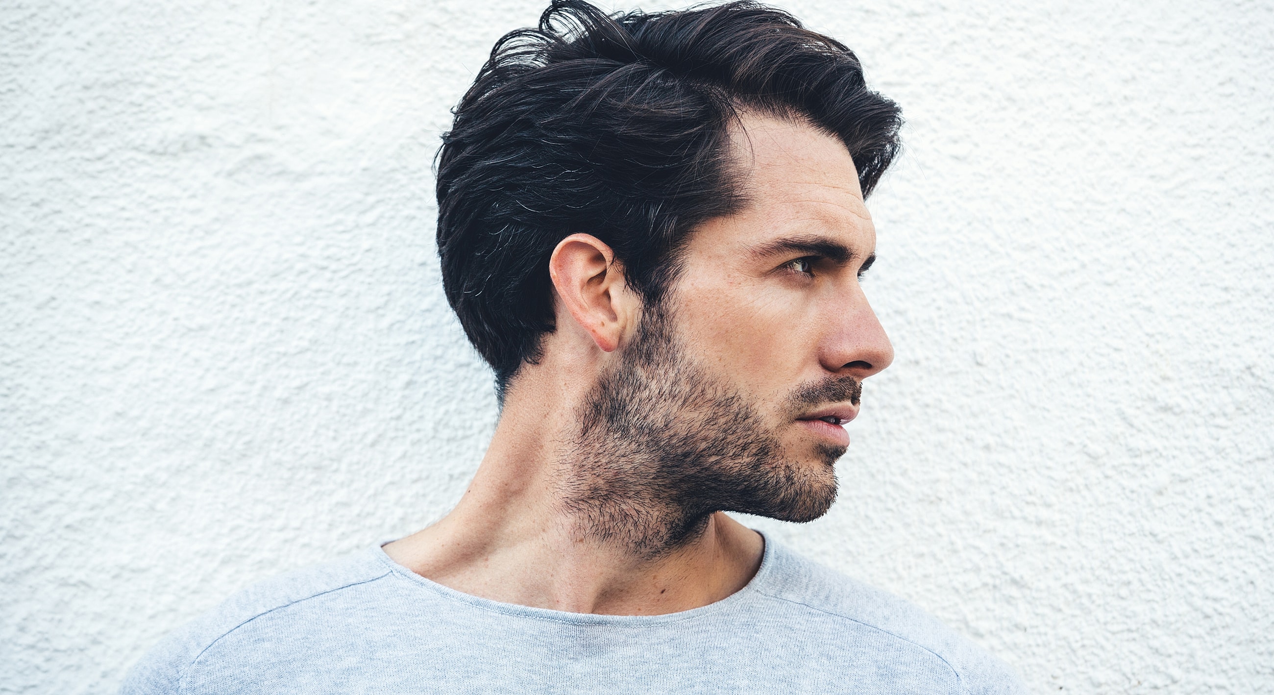 Man in profile against textured white background.