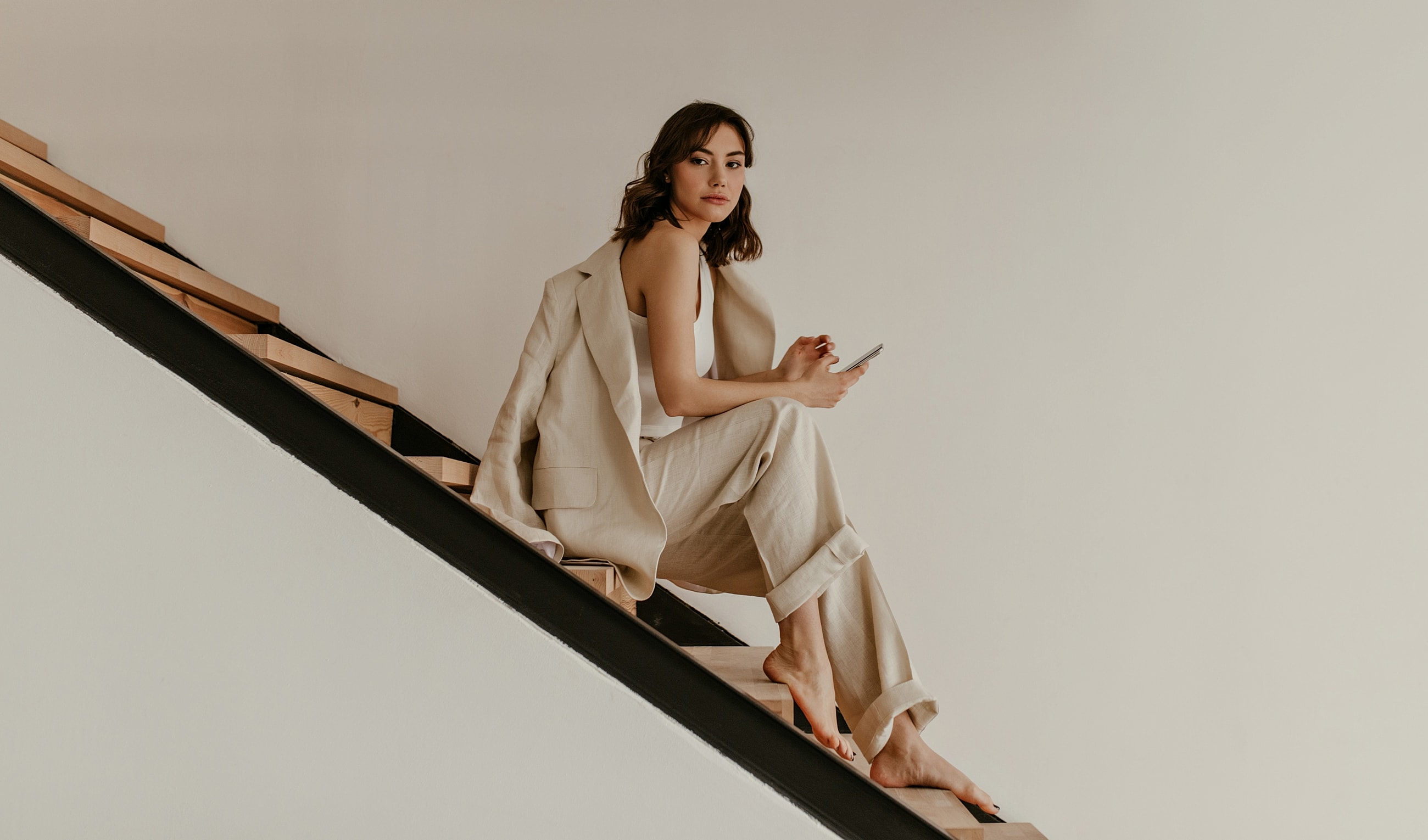 Woman sitting on stairs, holding smartphone.