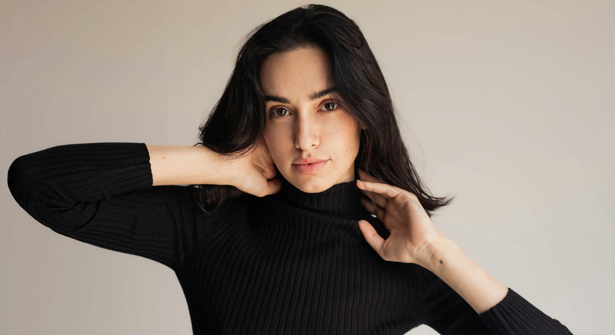 Young woman in black turtleneck sweater posing gracefully.