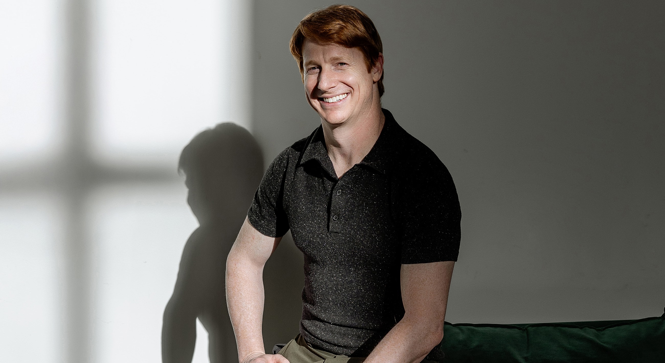 Smiling man sitting on a green couch.